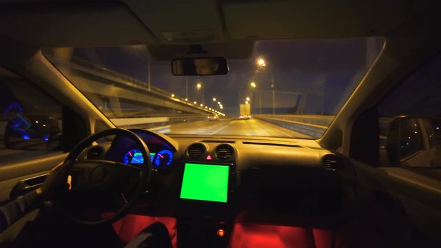 The man drive a vehicle on the bridge, evening night time, wide angle, inside view, green screen display on the panel, real time capture