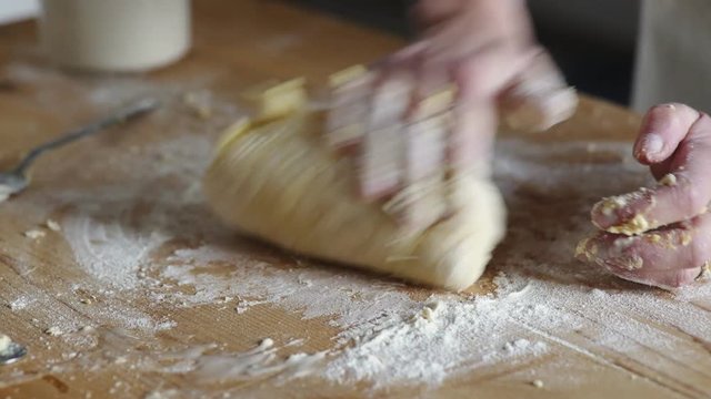 Hands of woman kneading the dough on wooden cutting board