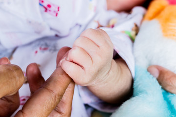 Close-up of newborn child touching mother hand