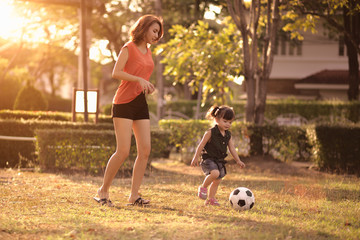 Young mother with daughter playing soccer