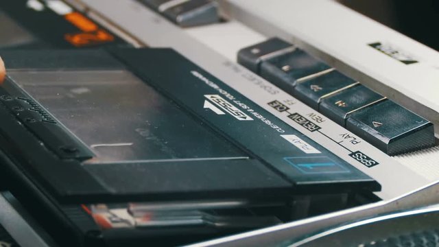 Opening the Cassette Deck, Inserting a Cassette and Playing a Tape Recorder. Vintage tape recorder Plays tape inserted therein. Close-Up. Tape in use sound recording in cassette player.
