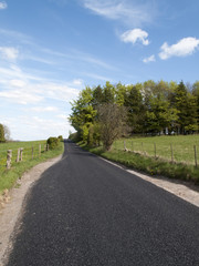 Single lane country road through countryside and farmland