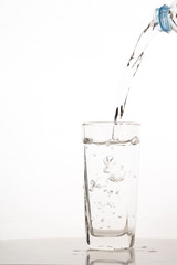 Pouring water from bottle into glass on a white background.