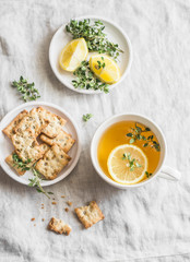 Lemon thyme green tea and homemade salt multi-seed cracker on a light table, top view