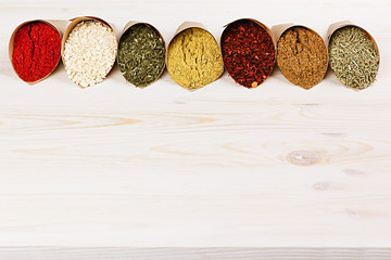Assortment of varied powder spices close-up on  white wooden board as  decorative border with  copy space.