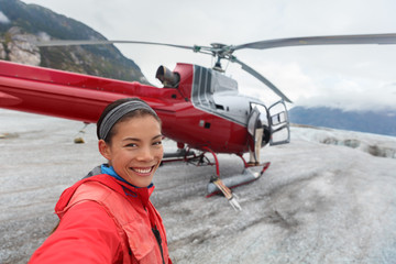 Happy tourist taking selfie picture on helicopter tour excursion. Asian woman cruise passenger on shore activity glacier walk hike in Alaska, USA. © Maridav