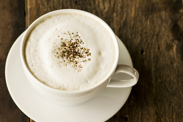 cappuccino coffee in white cup on wooden background