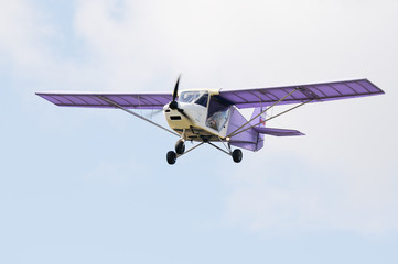 Naklejka na ściany i meble Private propeller-driven airplane flying in cloud sky