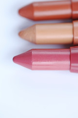 Pink, beige and brown lipstick pencil  on a white background