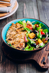 Greek salad and roasted chicken in plate on wooden table background. Top view with copy space