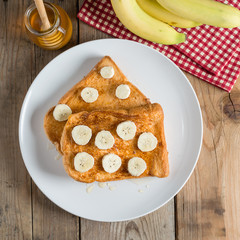 French toast topped with sliced banana and honey. Top view.