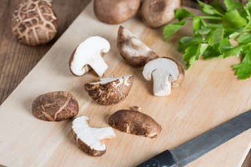 Sliced of Shiitake mushroom on wooden cutting board.