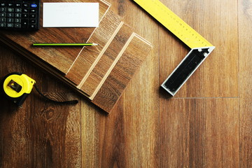 Laminate floor planks and tools on wooden background