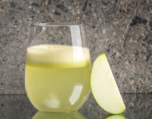 Glass of fresh apple juice on concrete background
