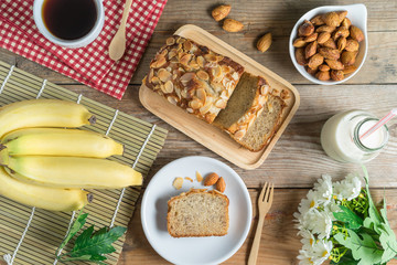 Banana cake topping with almond slice and banana, coffee, milk. Top view.