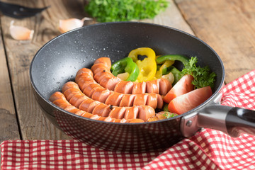 Grilled sausage on pan with garlic and bell pepper, tomato.