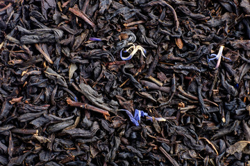 Dry tea with fruit and flower petals as background