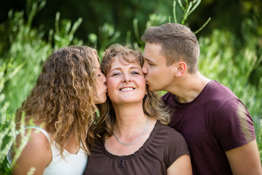 Beautiful smiling mother being kissed by her loving children.