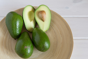 Fresh avacodos on wood dishe and one avacodo half cuted.