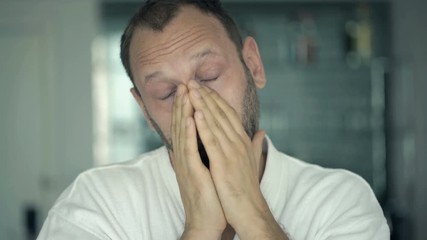 Portrait of sleepy man in bathrobe yawning at home
