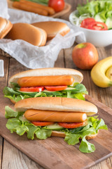 Hot dog with sausage, tomato, cucumber and lettuce.
