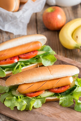 Hot dog with sausage, tomato, cucumber and lettuce.