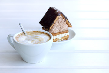 Table area for sweet coffee break/ Foamy cappuccino in a cup on the background of baking in the form of a sweet house 