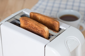 Close up of Burnt bread in toaster with cup coffee.