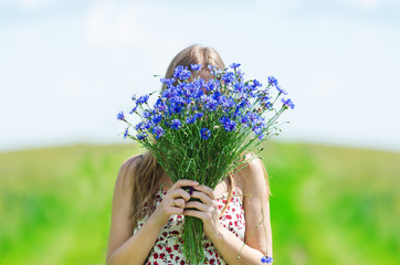 Beautiful young woman with a bouquet of flowers on the summer meadow