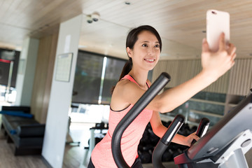 Sport Woman practice on Elliptical machine and taking selfie