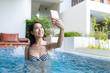 Woman enjoy in jacuzzi spa and taking selfie by mobile phone