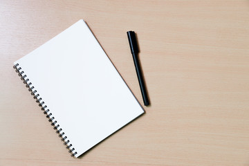 notebook paper note with a pen on wooden desk