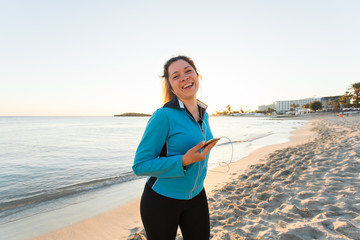 Outdoor sport, fitness gadget and people concept - Smiling female fitness holding smartphone with earphones.