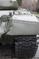 view of the front part of the green caterpillar of the tank standing on the ground with the wheels close-up - 145535563