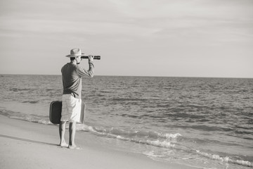 Back side view of man standing holding spyglass looking at natural ocean shore outdoors background. Traveler discovering journey, exploring escape or market opportunities. Sunny sky horizon