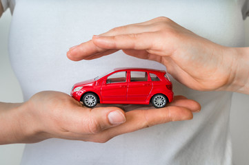 Red car in hands - insurance, rent and buying car concept