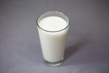 Milchglas, Glas mit Milch, grauer Hintergrund