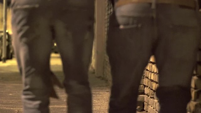 Close up on Legs of drunken men walking, stumbling on the street at night