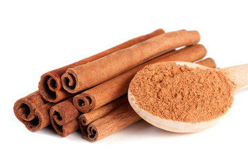 a stack of cinnamon sticks and powder with spoon isolated on white background