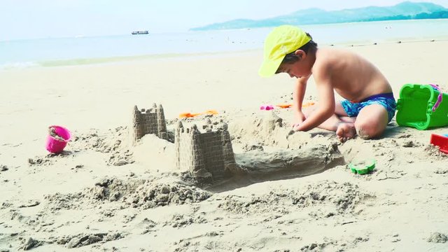 blonder bub spielt mit sand auf einem strand in thailand
