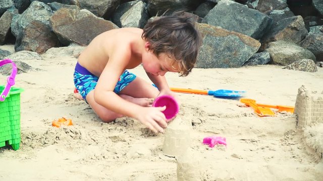bruder und schwester spielen mit sand auf einem strand in thailand