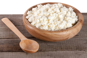 Cottage cheese in a wooden bowl on board with white background