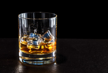 glass of whiskey with ice on a dark background