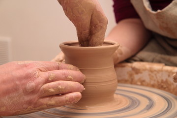 Hands of a potter, creating an earthen jar on pottery wheel.