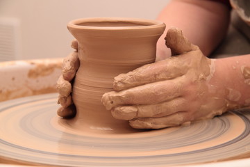 Fototapeta na wymiar Hands of a potter, creating an earthen jar on pottery wheel.