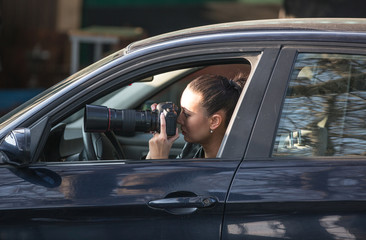 Girl papparazi with a camera in the car