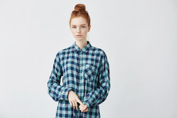 Confused beautiful redhead girl with big bun looking at camera.