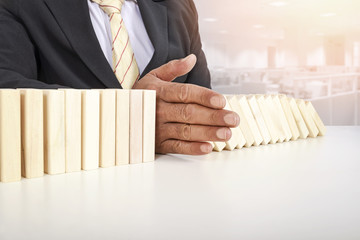 Businessman stop domino effect. Risk management and insurance concept, leadership has solution for...