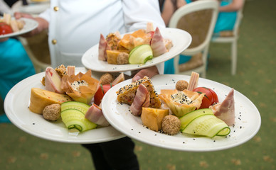 Waiter carrying plates with appetizers on some festive event