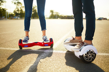 young man and woman riding on the Hoverboard in the park. content technologies. a new movement. Close Up of Dual Wheel Self Balancing Electric Skateboard Smart. on electrical scooter outdoors
